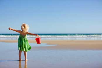 girl standing on beach with a bucket, CA